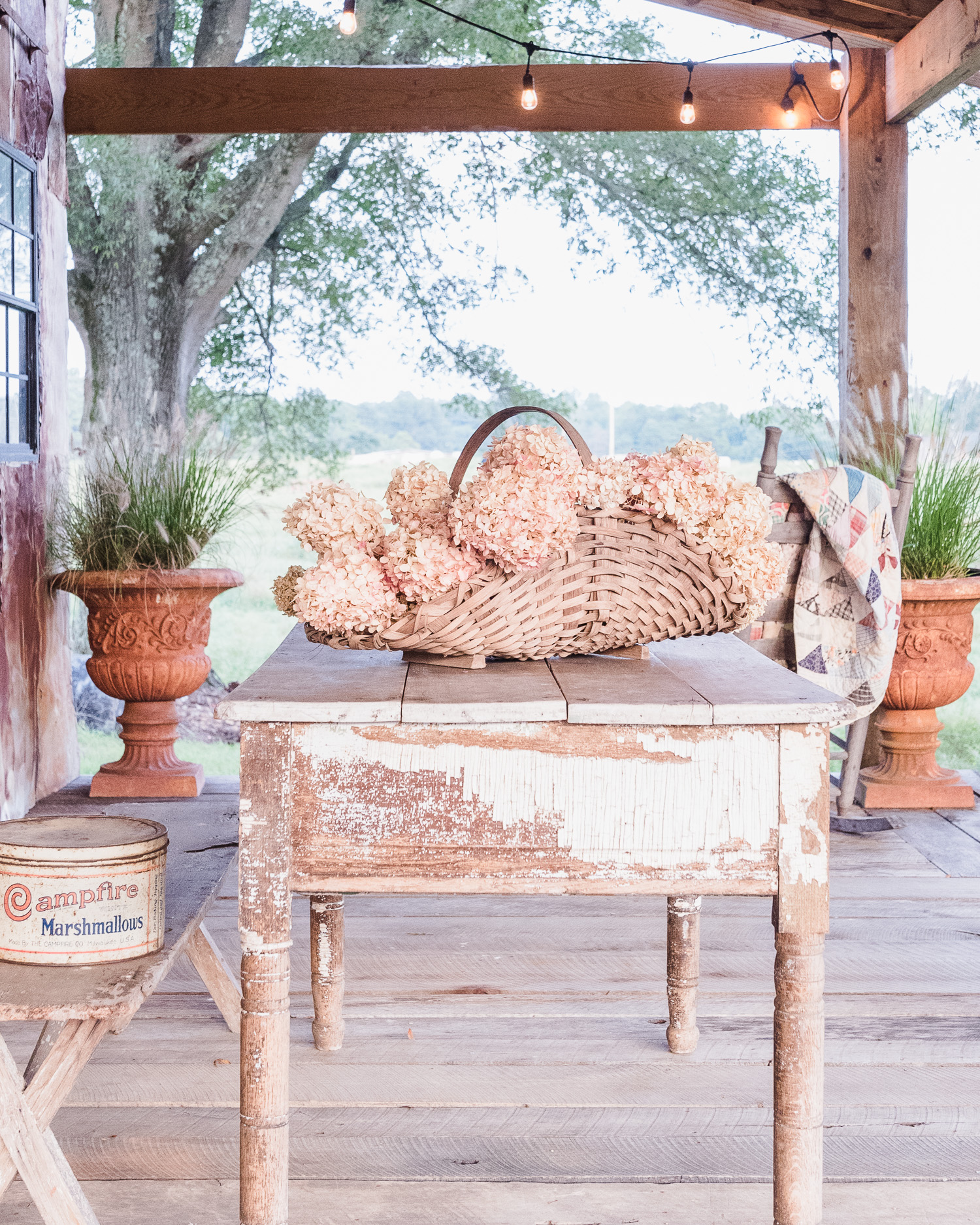 Simple Summer Styling on our barn porch. Dried hydrangeas, vintage baskets, tins, and an antique cutter quilt